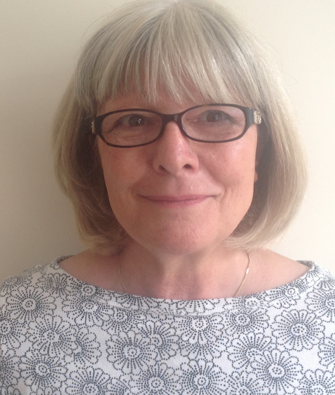 Caucasian woman with shoulder length grey hair and glasses
