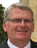Caucasian man with short grey hair and glasses