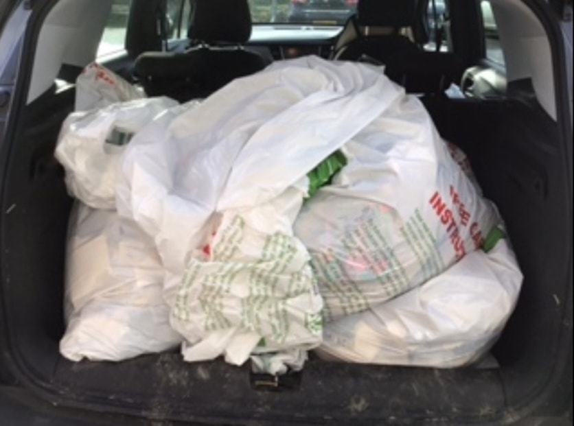 A photo showing the rear door of a car filled with sacks containing materials.