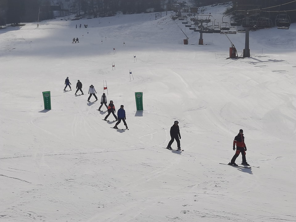 Several Snowfields Academy students are seen descending down a snowy slope on Skis from a distance during a school trip abroad.