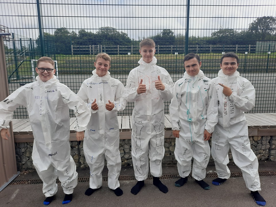 Students in all-in-one lab coats smiling for a photo